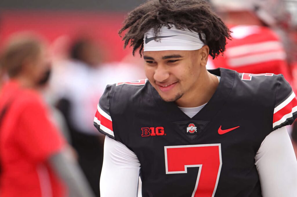 Smiling C J Stroud in Ohio State football uniform red and white with blurred stadium background Wallpaper
