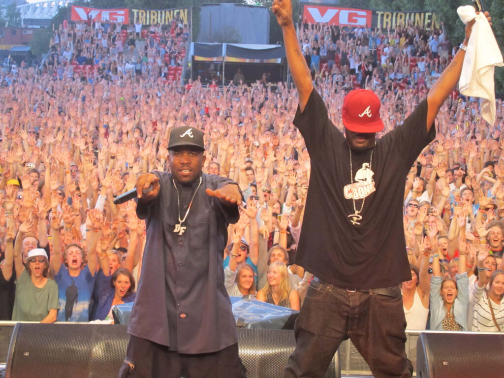 C-Bone and Big Boi perform live on stage at a packed concert with an energetic crowd background Wallpaper