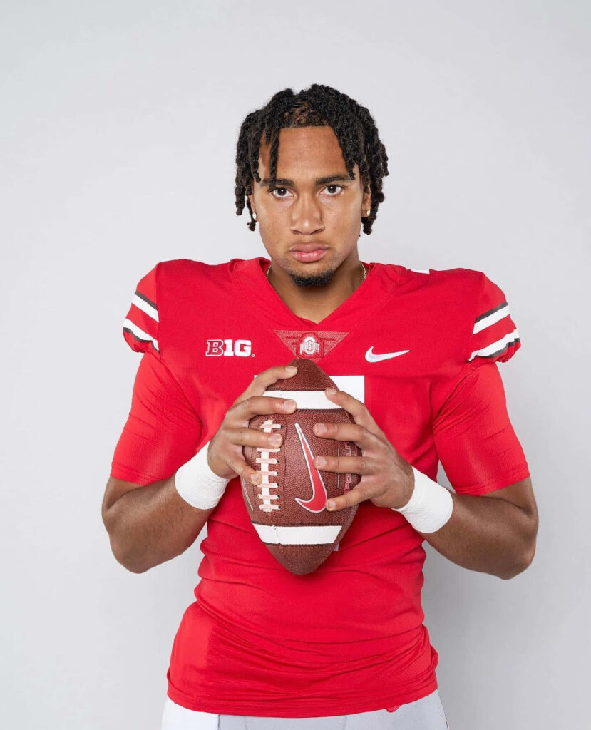 CJ Stroud in Ohio State football uniform holding ball with intense focus and dynamic energy Wallpaper