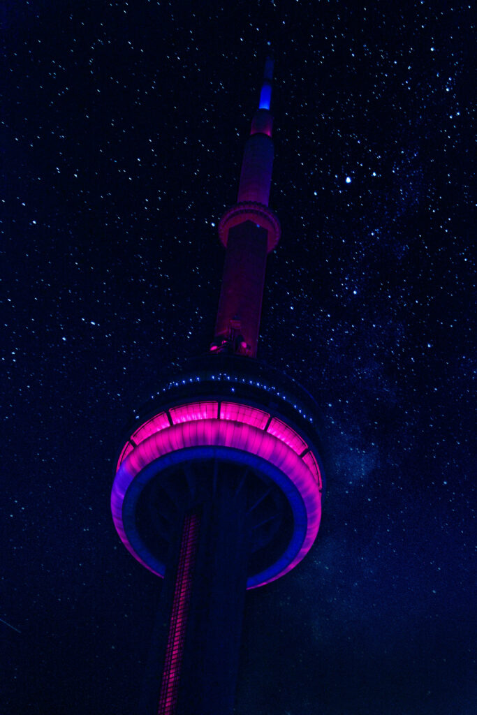 CN Tower glowing neon pink and blue under a vibrant starry night sky wallpaper background