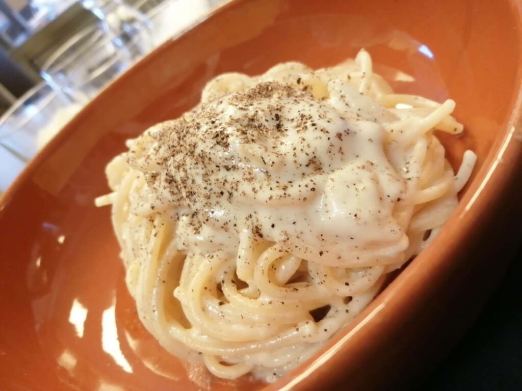 Cacio e Pepe Pasta on Vibrant Orange Plate - Creamy & Peppery Delight Wallpaper