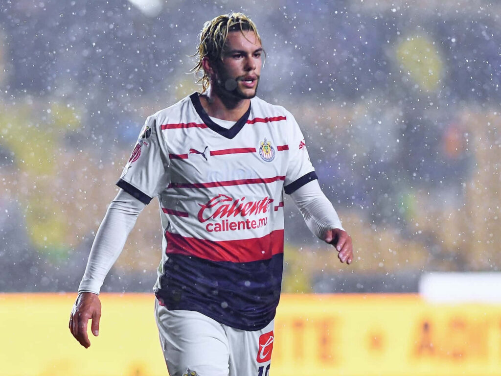 Cade Cowell in Chivas jersey playing soccer under dramatic rain and bright stadium lights Wallpaper