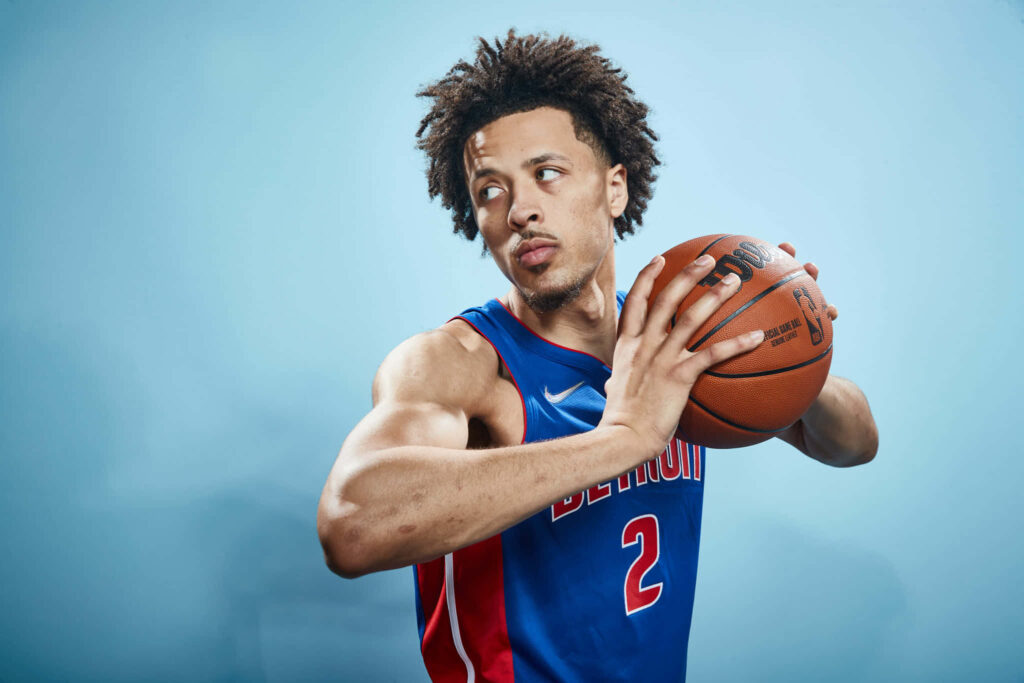 Cade Cunningham in Detroit Pistons jersey in action pose with intense focused expression blue background Wallpaper