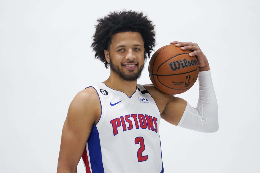 Cade Cunningham in Detroit Pistons jersey holding basketball on white background sports portrait Wallpaper