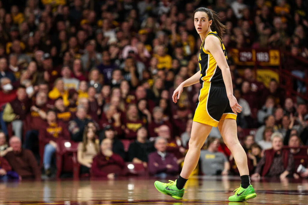 Caitlin Clark intense basketball action black yellow uniform bright green shoes stadium crowd wallpaper