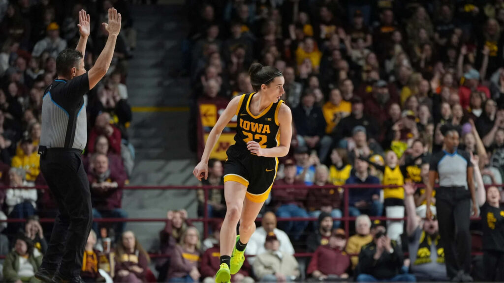 Caitlin Clark celebrates in Iowa basketball uniform with energetic crowd and arena lights Wallpaper