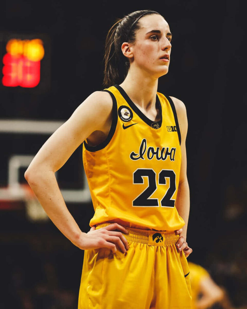 Caitlin Clark in yellow Iowa basketball uniform number 22 focused under arena lights wallpaper