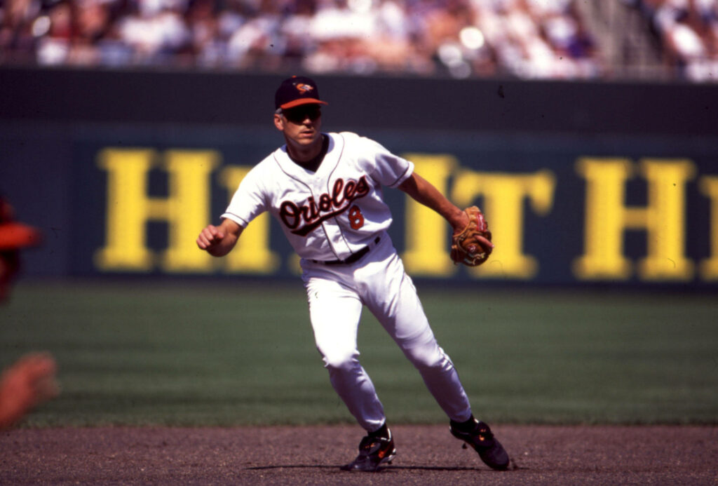 Cal Ripken Jr in white Orioles uniform batting during dynamic baseball game with stadium crowd Wallpaper