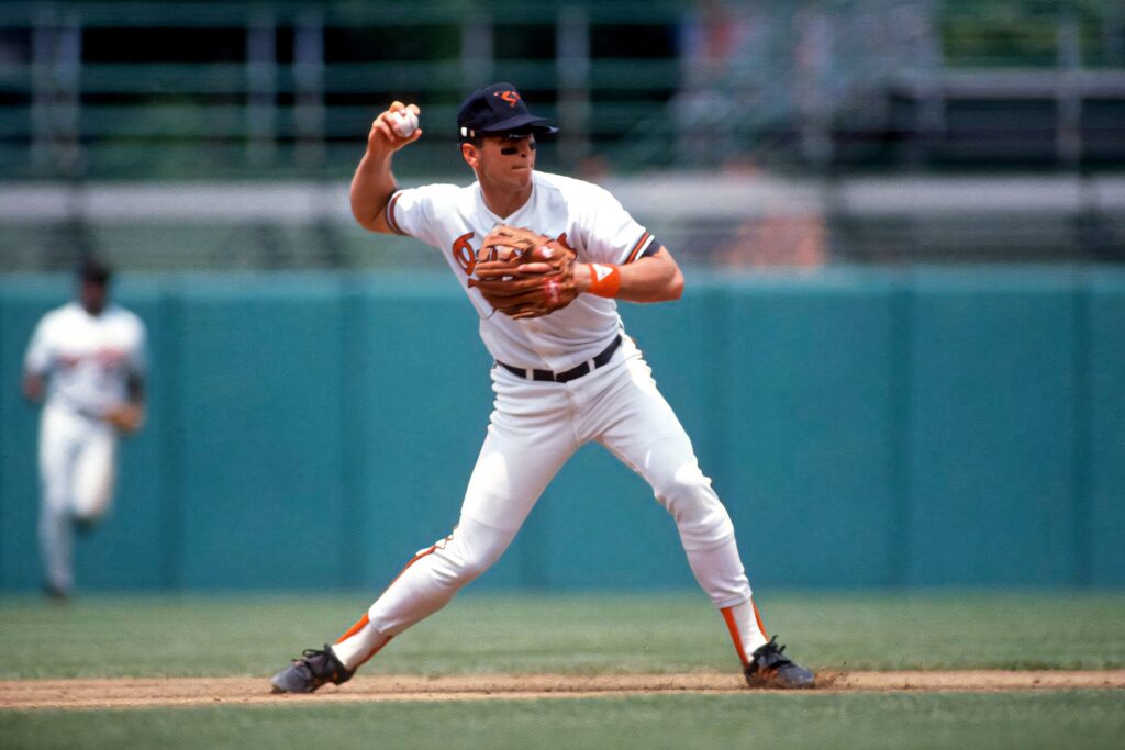 Cal Ripken Jr in Baltimore Orioles uniform focused on baseball field with vibrant stadium background Wallpaper