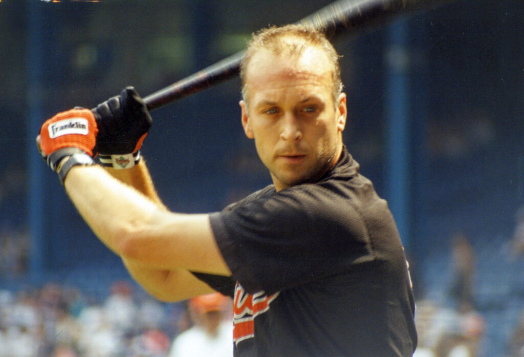 Cal Ripken Jr in black uniform gripping bat focused ready to hit in sunlit stadium wallpaper