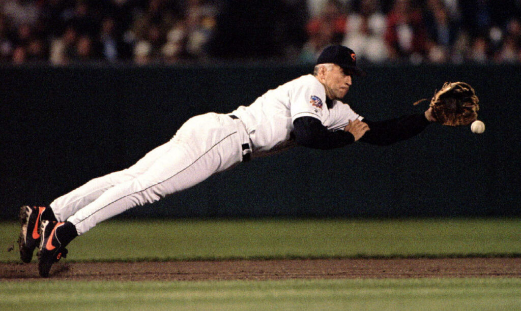Cal Ripken Jr mid-air catch baseball action white uniform intense moment dark background wallpaper
