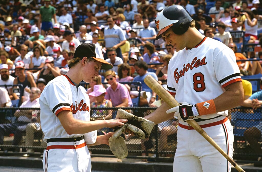 Cal Ripken Jr autograph signing in Orioles uniform number 8 with young fan at baseball stadium Wallpaper