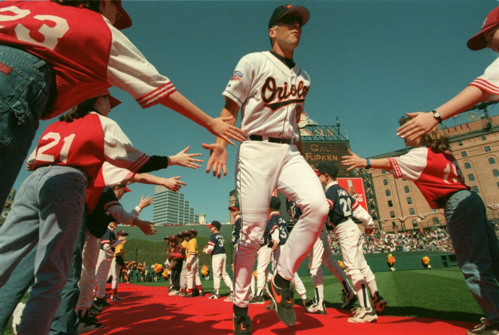 Cal Ripken Jr walking red carpet high-fiving Orioles fans under clear blue sky baseball legend Wallpaper