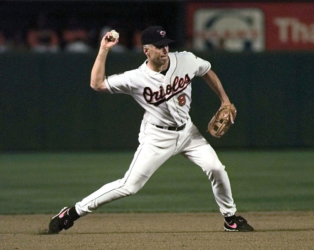 Cal Ripken Jr in Baltimore Orioles uniform throwing baseball on green field action wallpaper