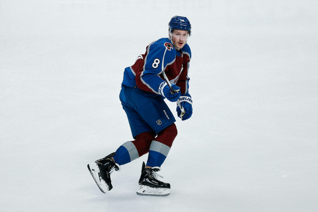 Cale Makar in Colorado Avalanche jersey skating on ice rink showcasing intense hockey action Wallpaper