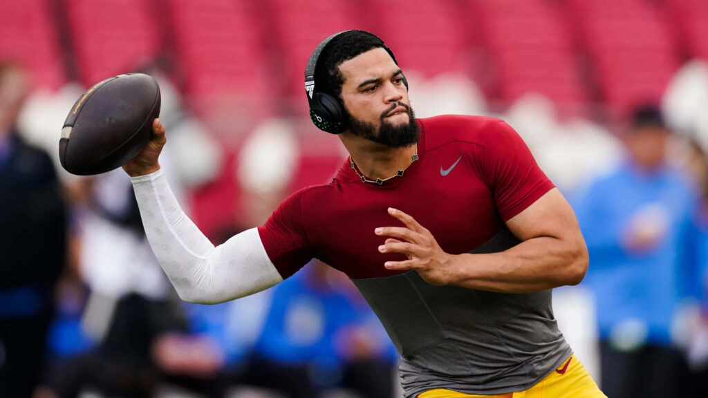 Caleb Williams throwing football in red Nike shirt with headphones during stadium training session Wallpaper