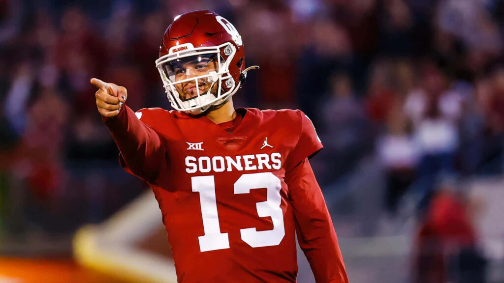 Caleb Williams Sooners quarterback number 13 in action pointing on field vibrant red white uniform Wallpaper