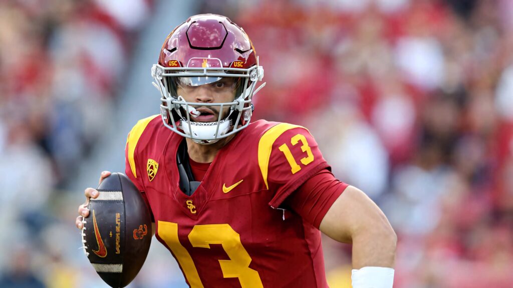 Caleb Williams USC quarterback in red gold uniform throwing football with focused expression Wallpaper