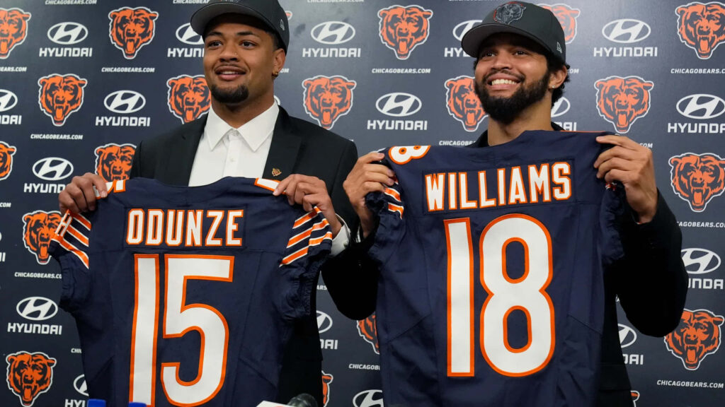 Caleb Williams and Rome Odunze hold Chicago Bears jerseys with vibrant navy blue orange background Wallpaper