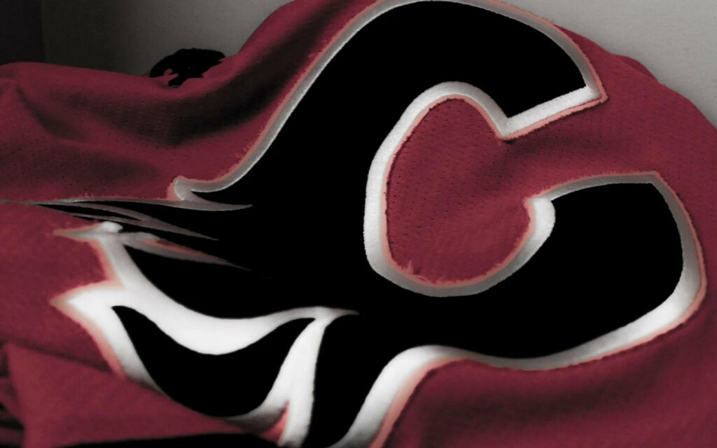 Close-up of Calgary Flames embroidered logo in black red and white on textured fabric wallpaper