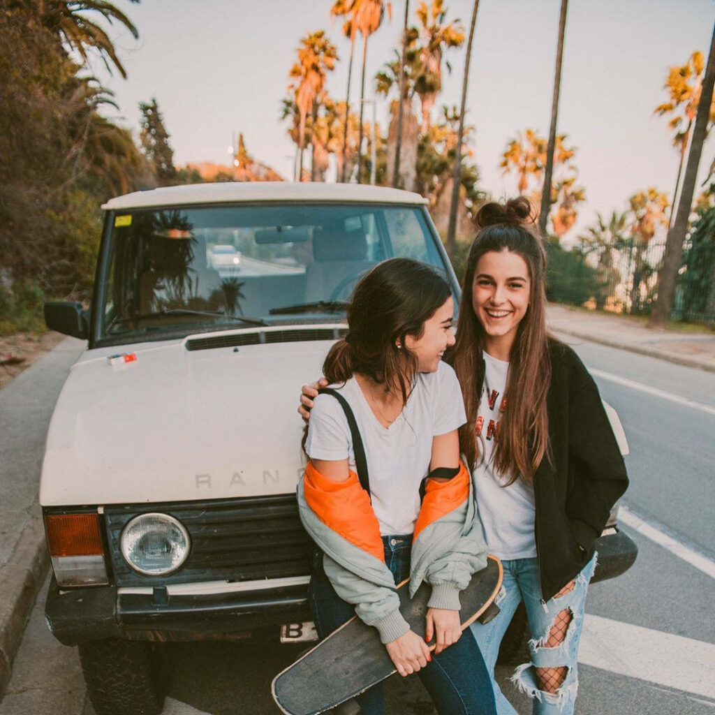 California Dreamin': Two Best Friends Bonding with a Skateboard by a Classic Car Wallpaper