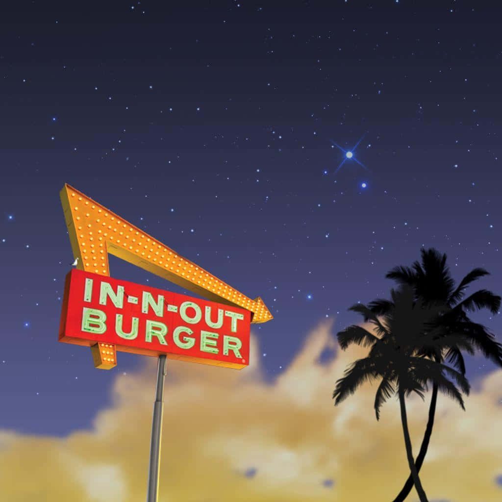 In-N-Out Burger sign glowing at night with palm tree silhouette under starry California sky wallpaper