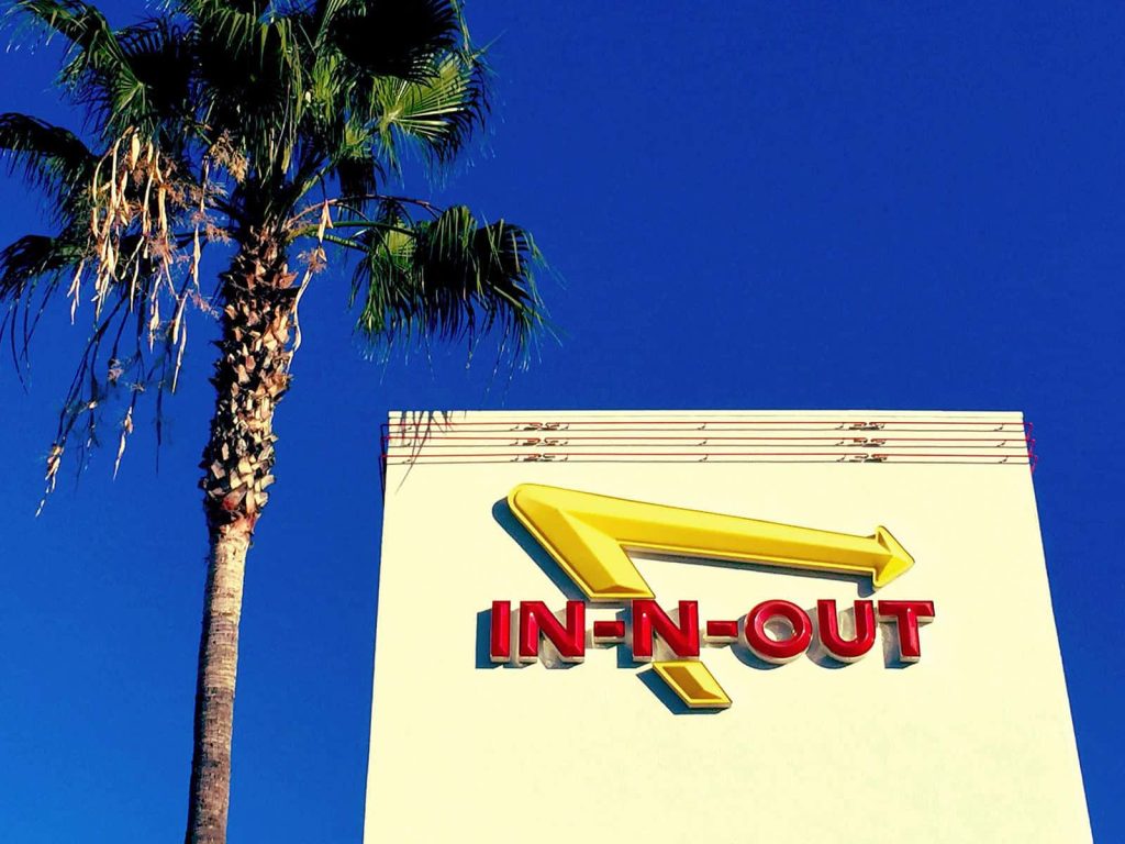 In-N-Out Burger logo with palm tree against deep blue sky West Coast California wallpaper background