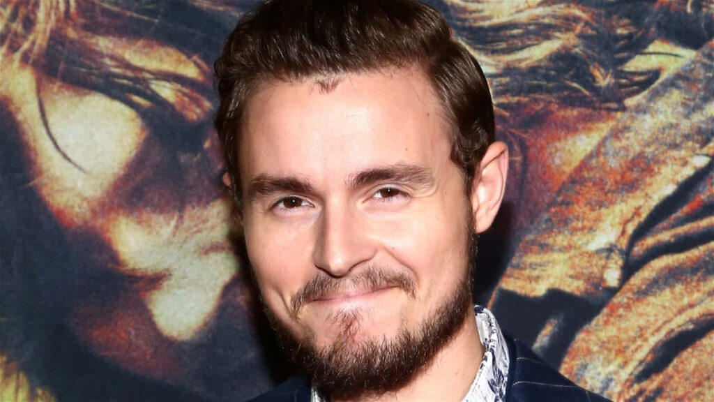 Callan McAuliffe close-up portrait with gentle smile warm earthy tones artistic vivid background wallpaper