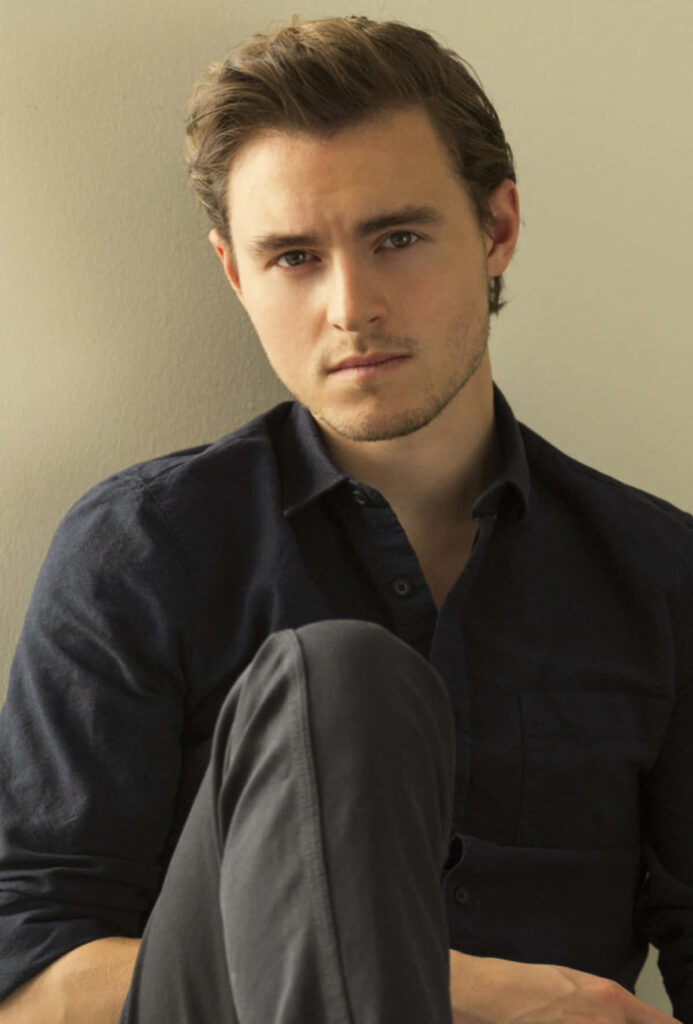Callan McAuliffe portrait wallpaper with soft lighting neutral background and classic dark shirt style