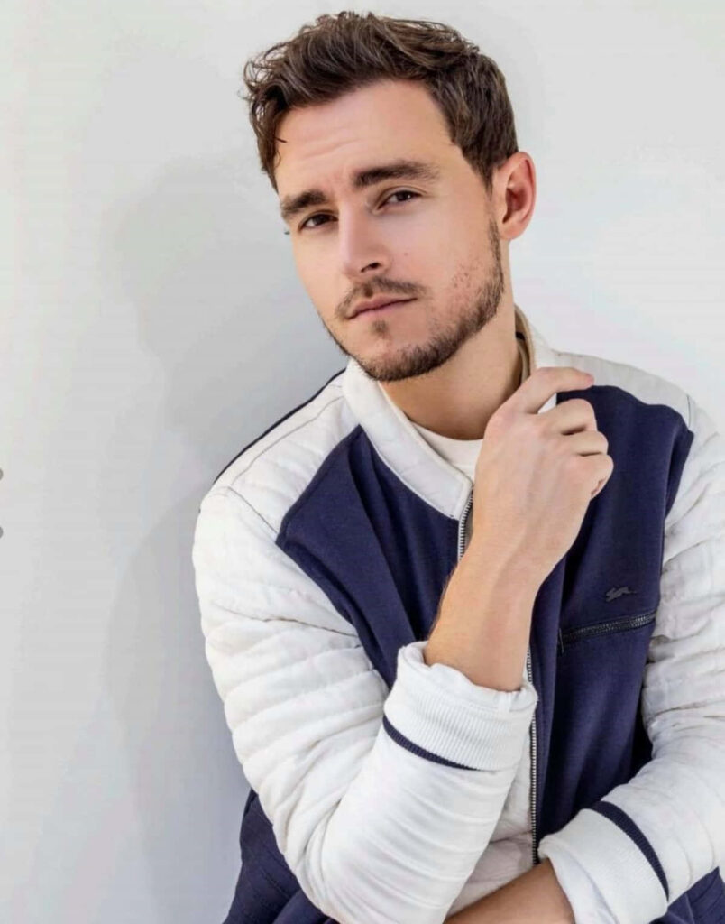Callan McAuliffe wearing navy white jacket in modern portrait with thoughtful expression and soft lighting Wallpaper
