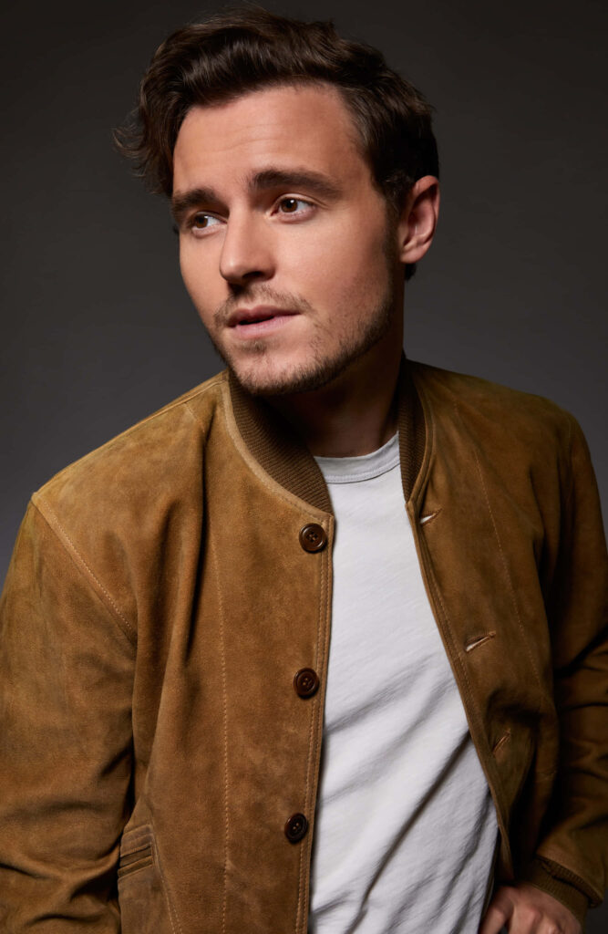 Callan McAuliffe portrait with brown suede jacket soft dramatic lighting dark background wallpaper