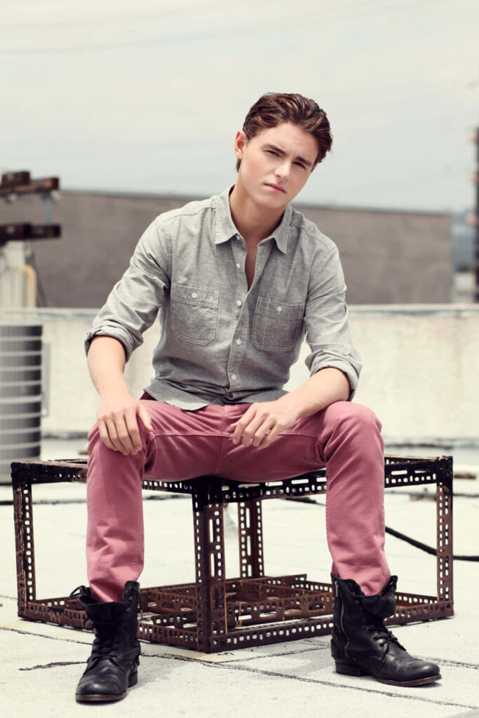 Callan McAuliffe casual rooftop portrait grey shirt pink pants industrial urban background natural light Wallpaper