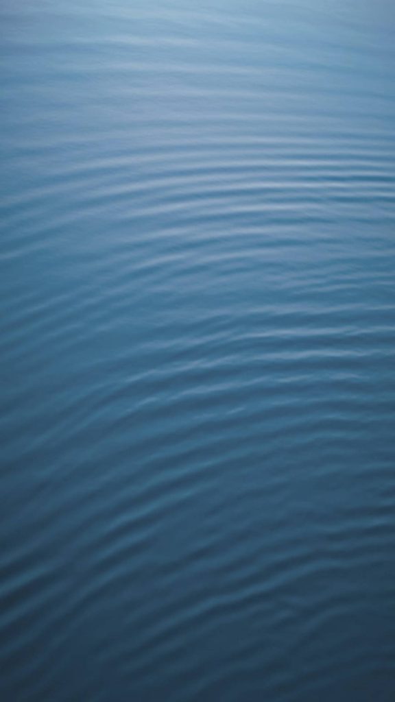 Minimalist iOS wallpaper with soft concentric ripples on deep blue calm water surface background