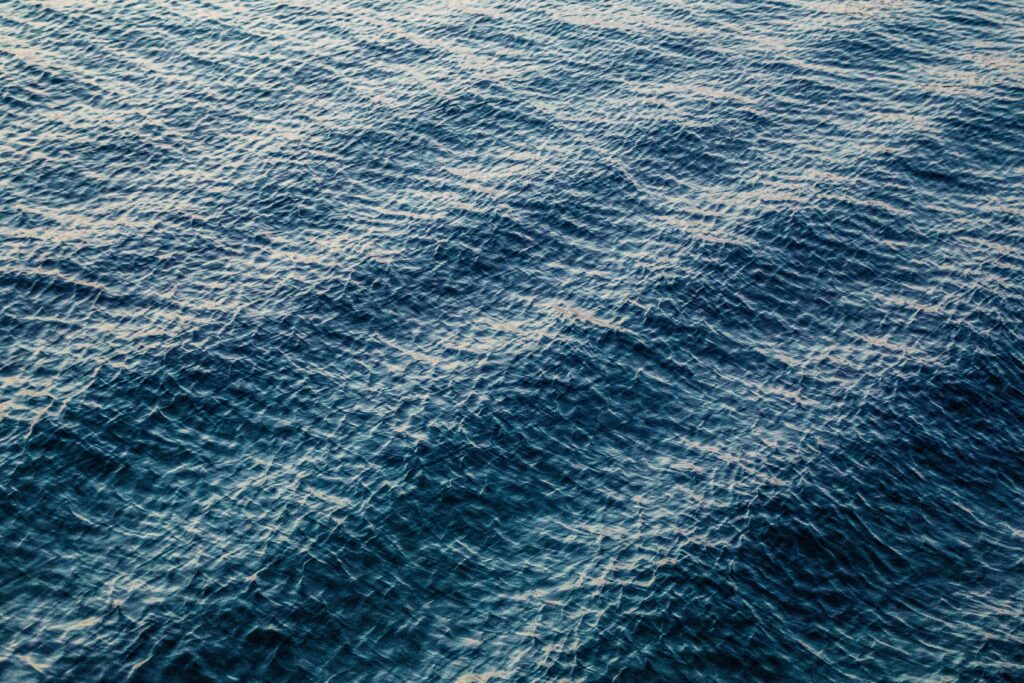 Calm deep blue ocean water with gentle ripples and natural light reflections wallpaper background