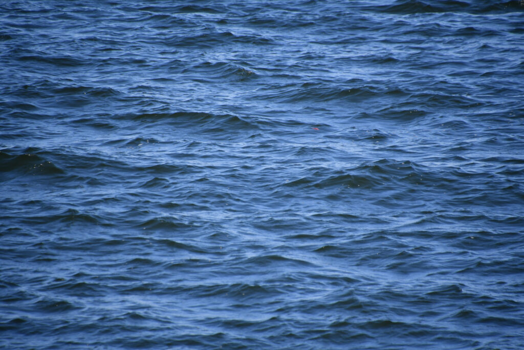 Serene deep blue ocean water with gentle waves and ripples textured wallpaper background