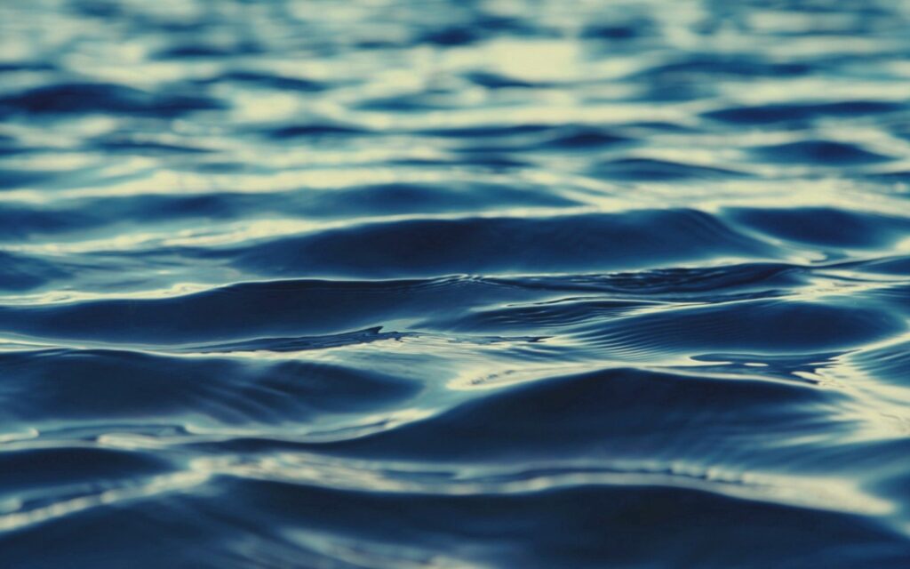 Serene deep blue sea wallpaper with gentle ripples and smooth reflective water background