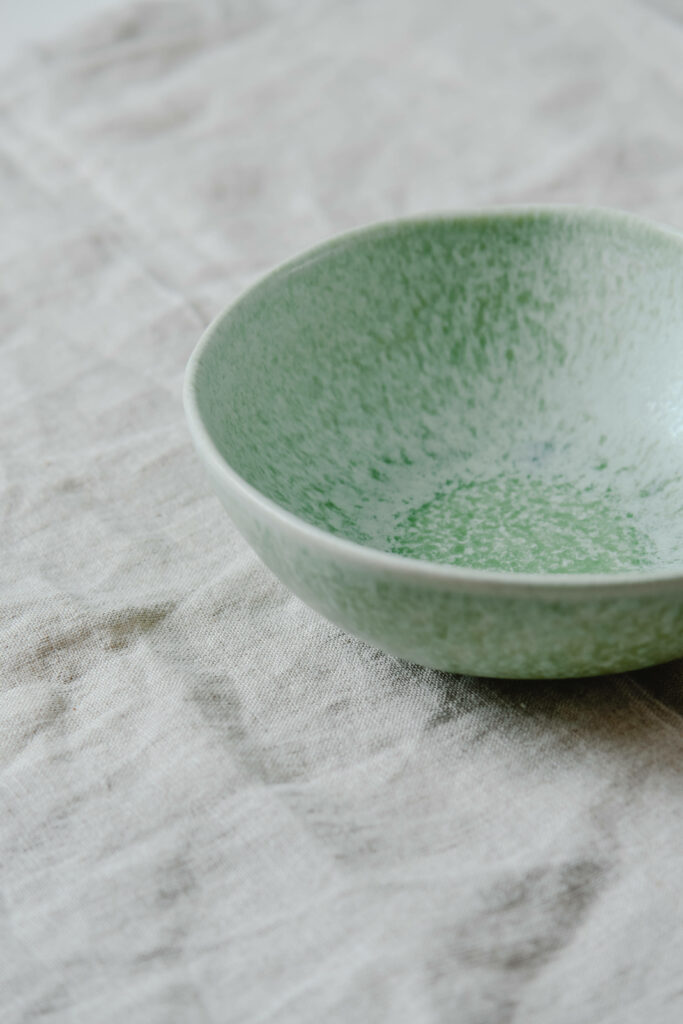 Minimalist Green Speckled Bowl Wallpaper on Neutral Fabric Background