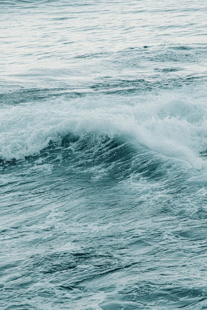 Gentle sea wave cresting with soft blue tones and foamy water calm ocean wallpaper background