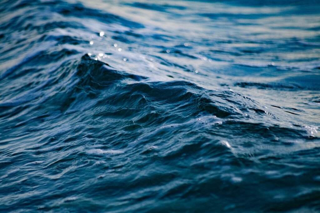 Dynamic ocean waves with deep blue ripples and light reflections for calming wallpaper background