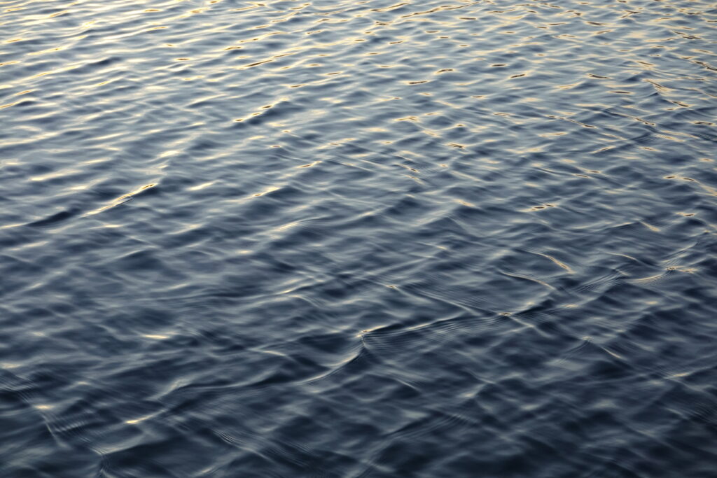 Serene calm water wallpaper with gentle waves blue and gold reflections peaceful natural background