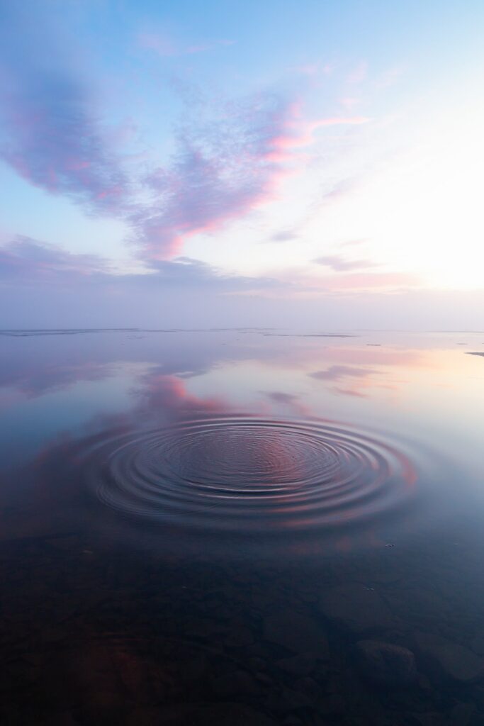 Calm water ripples reflecting pastel clouds and serene blue pink skies peaceful wallpaper background