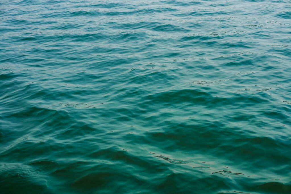 Calming blue green sea water wallpaper with gentle ripples and small natural waves background