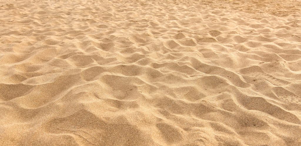Close-up of golden sand with wind ripples on beach calm textured natural wallpaper background