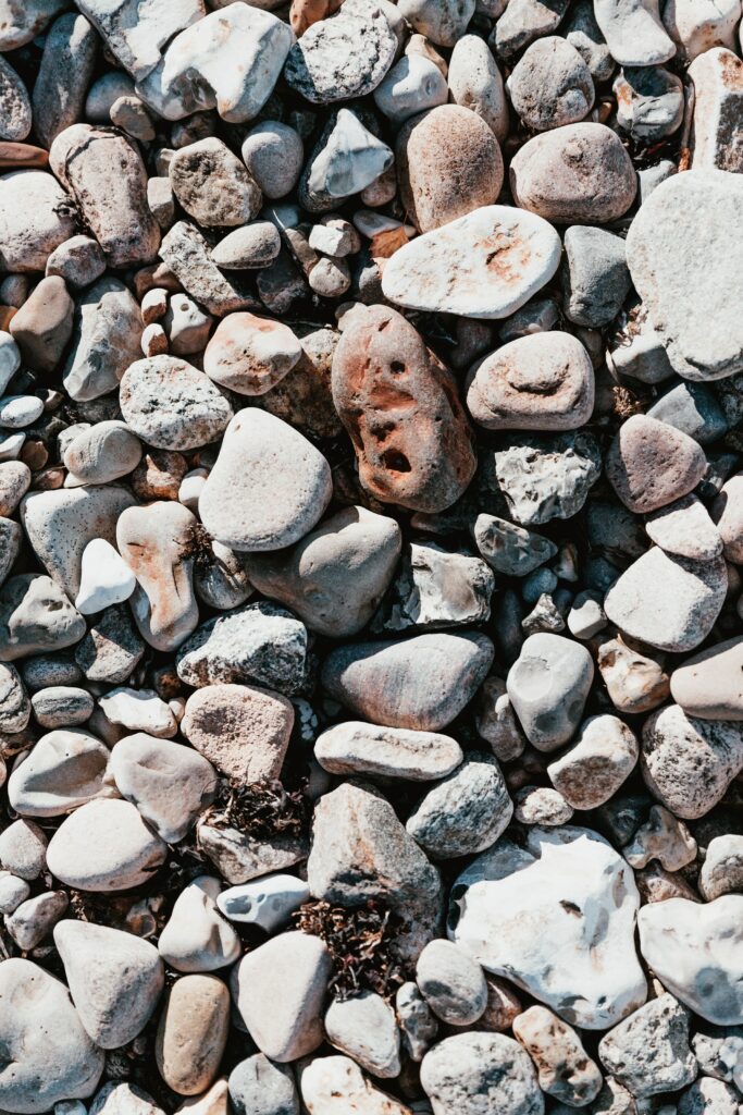 Smooth sea stones in gray beige and white creating a calming textured natural coastal wallpaper background