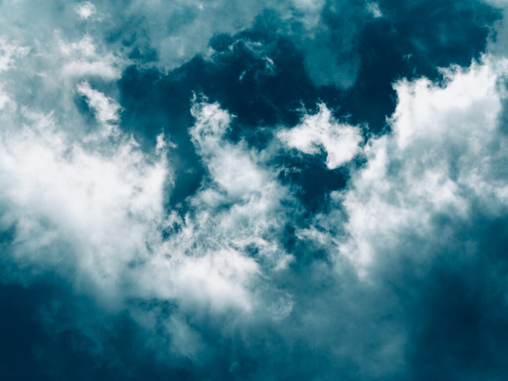 White porous clouds drifting over deep blue sky creating serene natural textured wallpaper background