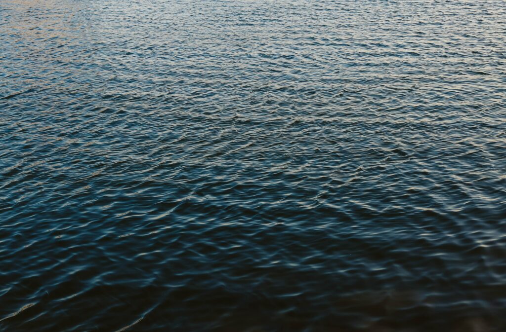 Calm deep blue water wallpaper with gentle ripples and soft natural light reflections