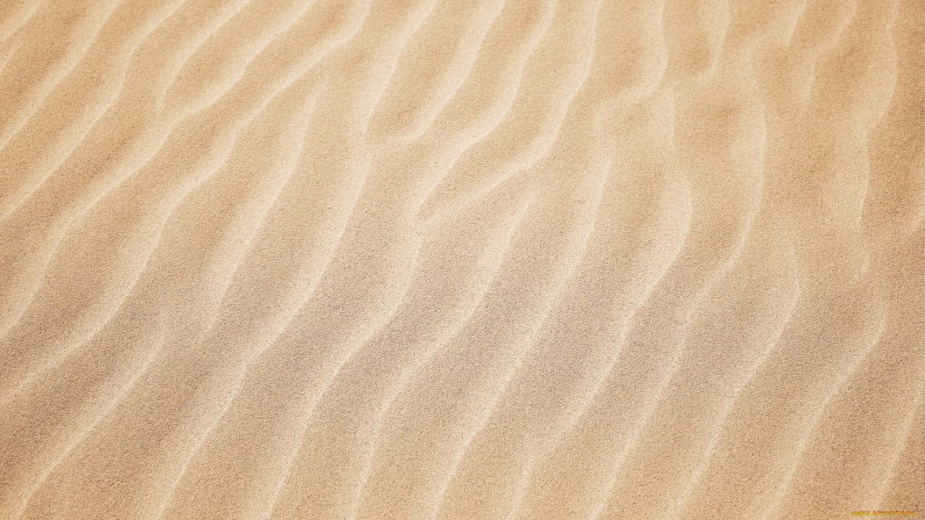 Close-up of flowing golden brown desert sand dunes with intricate wind-carved wave patterns Wallpaper