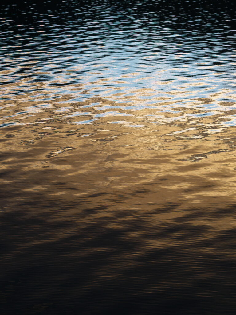 Serene seascape wallpaper with gentle waves reflecting golden and dark tones for calm ambiance