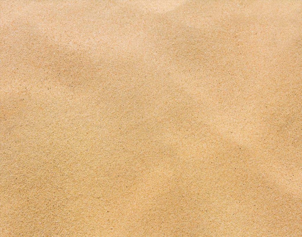 Close-up of golden sand grains detailed texture natural light calming minimalist wallpaper background