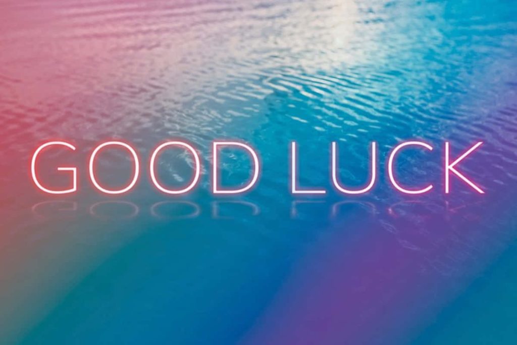 Good Luck neon sign glowing above rippling pink and blue water digital wallpaper background